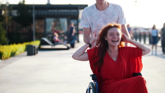 Guy Rolls A Happy Disabled Girl In A Wheelchair On The Waterfront
