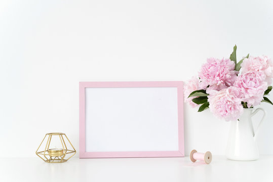 Pink landscape frame mock up with a pink peonies, candle and silk ribbons beside the frame, overlay your quote, promotion, headline, or design, great for small businesses, lifestyle bloggers and
