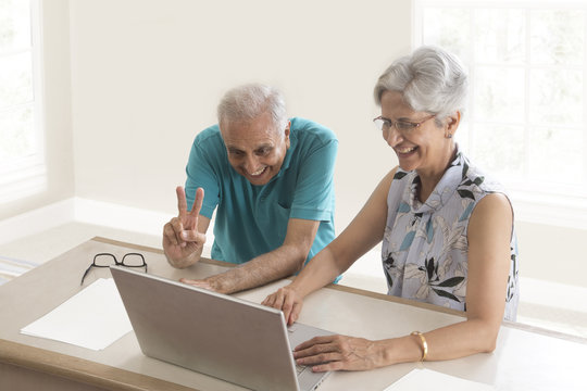 Senior couple using webcam on laptop