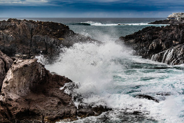 Obraz premium Seascape with black volcanic rocks, waves and splashes