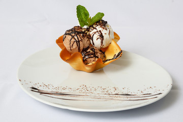 White and chocolate ice cream in a waffle form with the leaves of mint and chocolate cream on a...