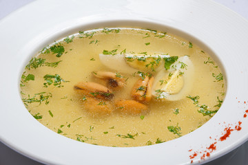 Soup with dumplings, egg and greenery. White background. Yellow.