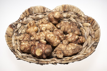 Jersalem Artichoke (Helianthus tuberosus) vegetable in wicker basket isolated on a white studio background.
