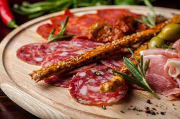 meat sliced proshto, salami, olives and pepper paprika on a wooden plate