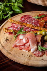 meat sliced proshto, salami, olives and pepper paprika on a wooden plate