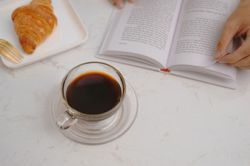 Still life details, cup of coffee and cake with book on table in coffee shop cafe