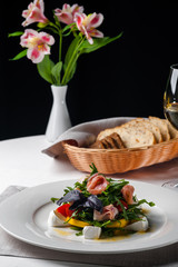 dish in the restaurant fresh salad with basil, prosciutto, tomato and mozzarella