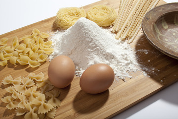 composition with eggs, spaghetti, macaroni, vermicelli and stirrer eggs on a wooden kichen cutting board