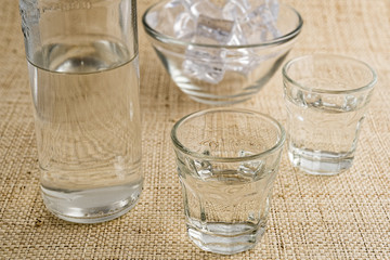 Glasses and bottle of traditional drink Ouzo or Raki on natural matting