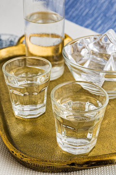 Glass and bottle of traditional drink Ouzo or Raki on bronze dish