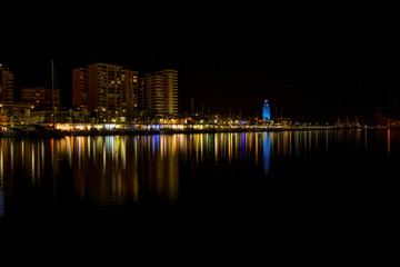 Fototapeta premium Spain, Malaga, a body of water with a city in the dark
