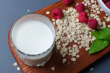 The concept of a healthy diet. Oatmeal, raspberry, milk, mint leaves on a dark cutting Board.