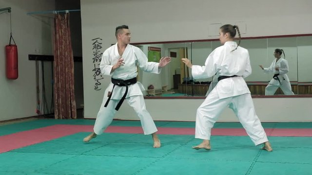 A young man with a muscular body and a woman practicing martial arts Goju-Ryu Karate-Do super slow motion