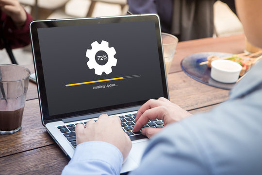 Businessman waiting for installing update process with gearbox percentage progress and loading bar on laptop / computer at the outdoor cafe