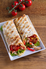 Chicken caesar salad wraps with bacon, tomatoes, lettuce and cheese. Tortilla, burritos, sandwiches twisted rolls