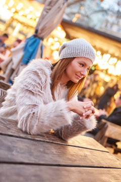 Portrait of a smiling beautiful young woman while sitting in a christmas market.