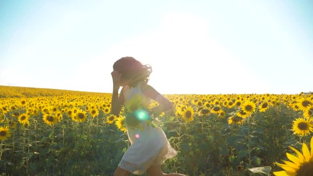 Happy little girl running happy free lifestyle across the field with sunflowers. slow motion video . smelling big sunflower on summer field. Delight of a pleasant smell. Summer holiday. concept