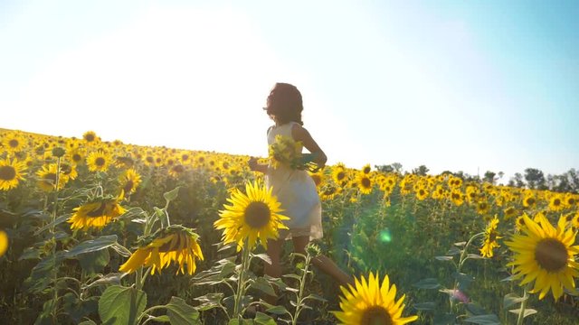 Happy little girl running happy free across the field with sunflowers. slow motion video . smelling big sunflower on summer field. Delight of a pleasant smell. Summer holiday. concept happiness girl