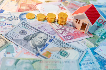 Real estate or property investment. Home mortgage loan rate. Saving money for retirement concept. Coin stack on various of international banknotes with house model on table. Business growth concept.