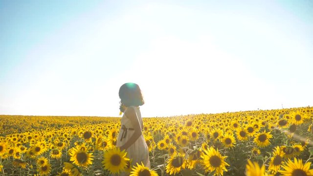 Happy little girl running happy free across the field with sunflowers. slow motion video . smelling big sunflower on summer field. Delight of a pleasant smell. lifestyle Summer holiday . concept