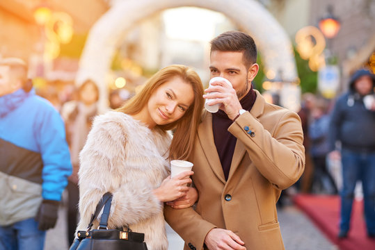 A beautiful young couple drinking mulled wine in a christmas market.