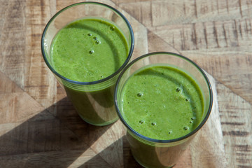 Fresh green healthy smoothie in sunlight on wooden background. 
