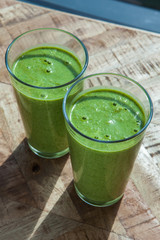 Fresh green healthy smoothie in sunlight on wooden background. 