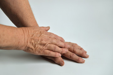 Fototapeta premium Hands of an elderly woman on a white background. Hands with wrinkles