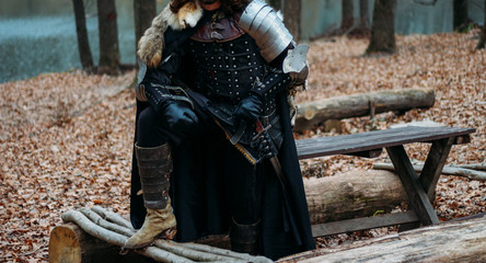 Medieval knight with sword in armor as style Game of Thrones in the forest.holds the sword