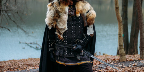 Medieval knight with sword in armor as style Game of Thrones in the forest