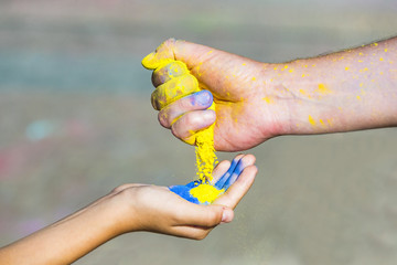 The man's hand pours into the children's paint during the celebration of the Holi holiday. 