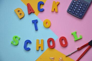 School office supplies with copy space. Back to school text concept. inscription flattering back to school on a colorful bright abstract  Top view.