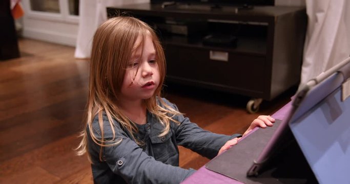 four years blonde cute child using tablet, singing and dancing on wooden parquet floor of at living room home indoor
