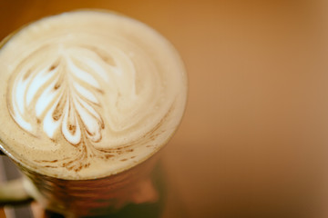 A Cup of hot latte art coffee on brown table