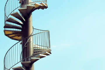 Spiral staircase in front of blue sky with copy space