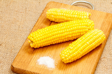 Cutting board with boiled corn on table