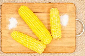 Cutting board with boiled corn on table