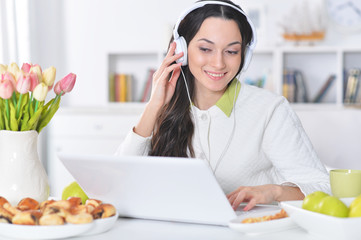 Obraz na płótnie Canvas Beautiful young woman in headphones using laptop
