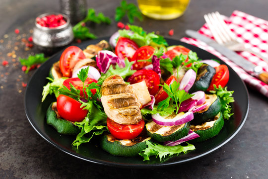 Salad with fresh and grilled vegetables and mushrooms. Vegetable salad with grilled champignons. Vegetable salad on plate. Healthy vegetarian food