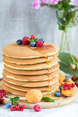 Fresh delicious pancakes with summer berries on light background.