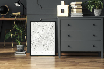 Map poster placed on the floor in real photo of dark grey room interior with fresh plants, gold...