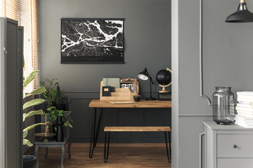 Map poster hanging on the wall in real photo of open space room interior with hairpin bench and...