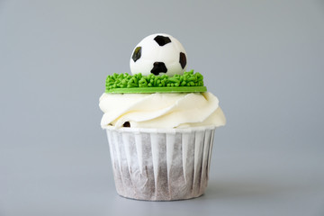 Chocolate cupcake on a football theme with white whipped cream decorated with green grass and...