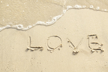 Fototapeta na wymiar Love written on the beach by the sea in the morning