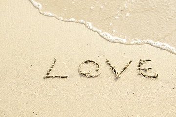 Love written on the beach by the sea in the morning