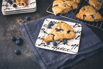 Homemade Blueberry Scones on a White Bon Appetite Dish; More Scones in Background on Wire Rack;...