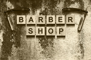 Concept Barber Shop. An inscription on wooden cubes against the background of an old vintage wall. Toned. Sepia.