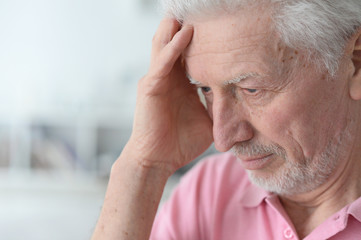Portrait of senior man with headache at home