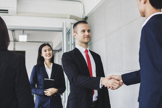 Manager, businessman, Europe investor or boss shake hand  with Asian Entrepreneur and  successful  big project deal in meeting  by interpreter standing near to translate