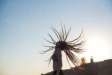 Young girl with flying dreadlocks at sunset in profile. Girl feel freedom and enjoying the nature